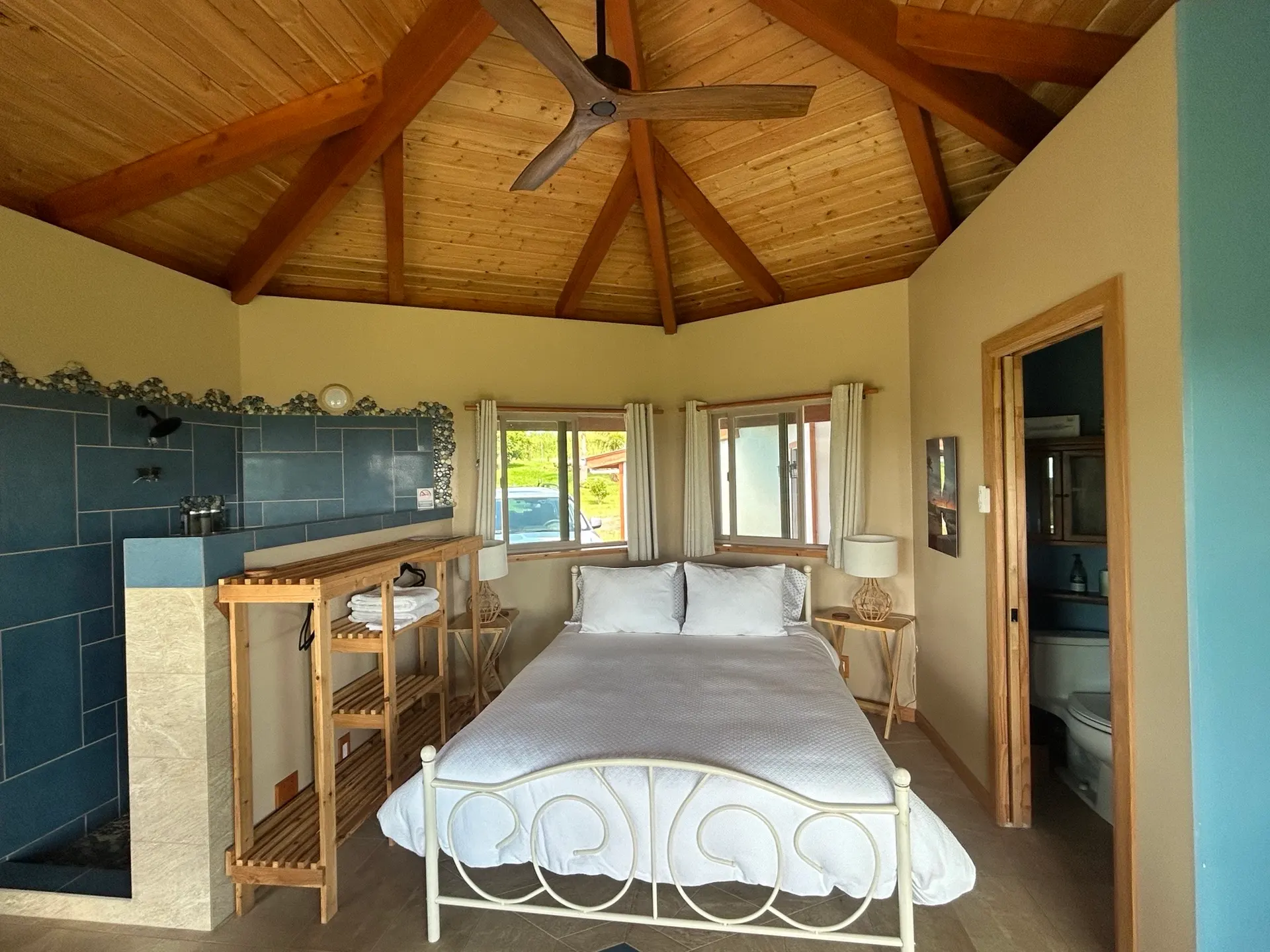 Queen bed beneath the wood-beamed ceiling of a Hilo Airbnb bungalow